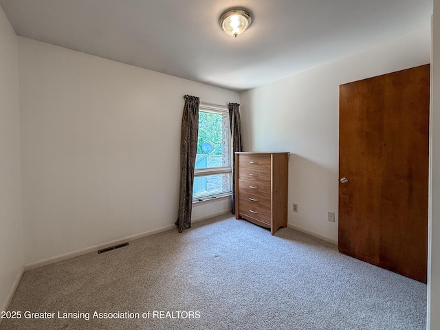 515 N Putnam St Unit B, Williamston, MI 48895 - unfurnished bedroom featuring light carpet and baseboards