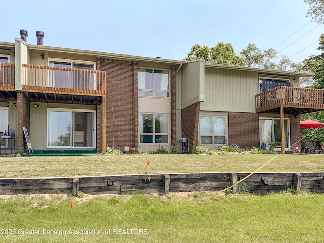 515 N Putnam St Unit B, Williamston, MI 48895 - back of house with a balcony, brick siding, and a lawn