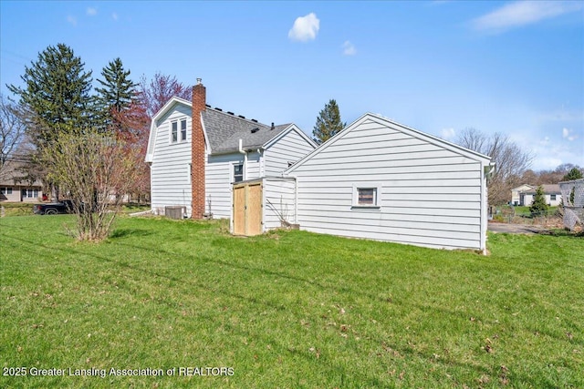 rear view of house with a yard, central air condition unit, and a chimney