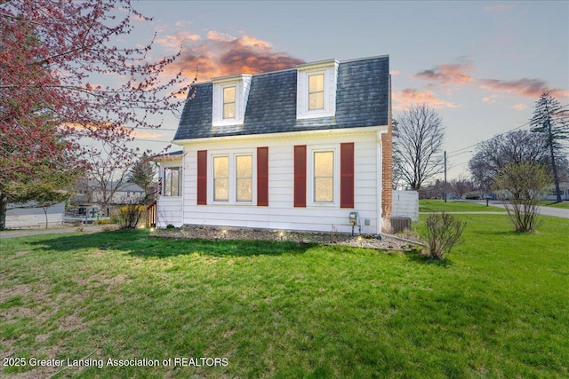 view of front of house with a shingled roof, mansard roof, a front yard, and central air condition unit