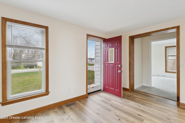 foyer with light wood-type flooring, visible vents, baseboards, and a healthy amount of sunlight