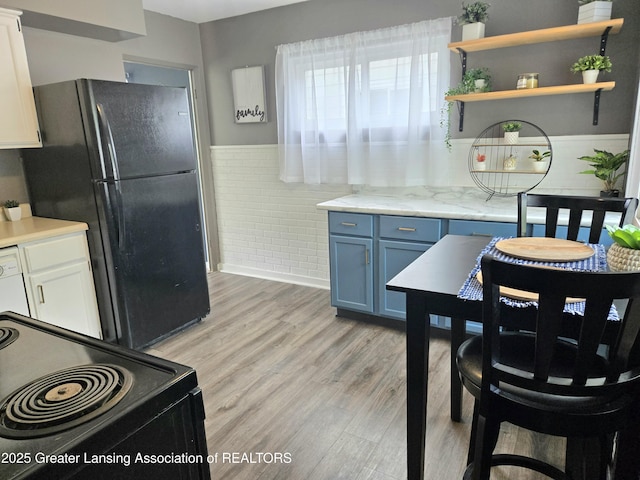 2032 Hillcrest St, Lansing, MI 48910 - kitchen featuring black appliances, blue cabinets, wainscoting, light wood-style floors, and open shelves