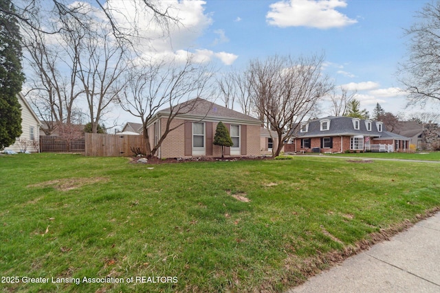 view of front of home with fence, a front lawn, and brick siding