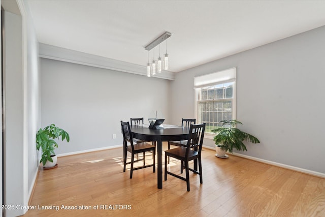 dining area with light wood-style floors, baseboards, and ornamental molding