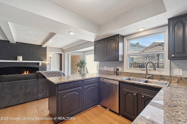 kitchen featuring dishwasher, a sink, a peninsula, light wood-style flooring, and open floor plan
