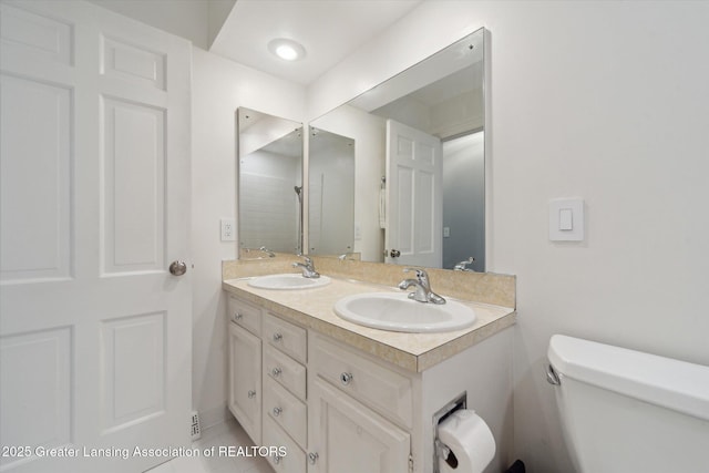 bathroom featuring double vanity, toilet, and a sink