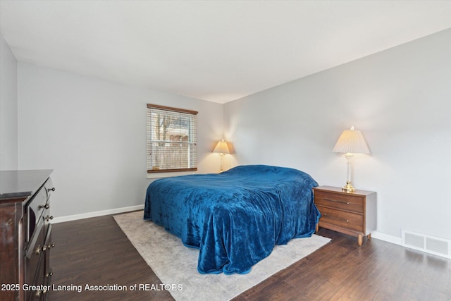 bedroom with baseboards, wood finished floors, and visible vents