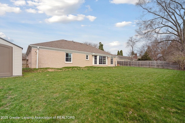 back of house featuring a fenced backyard, a storage unit, an outdoor structure, and a yard