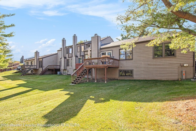 rear view of property featuring a lawn, stairs, and a deck