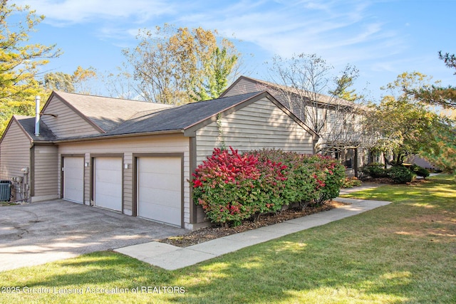 view of property exterior with an attached garage, driveway, a yard, and central AC