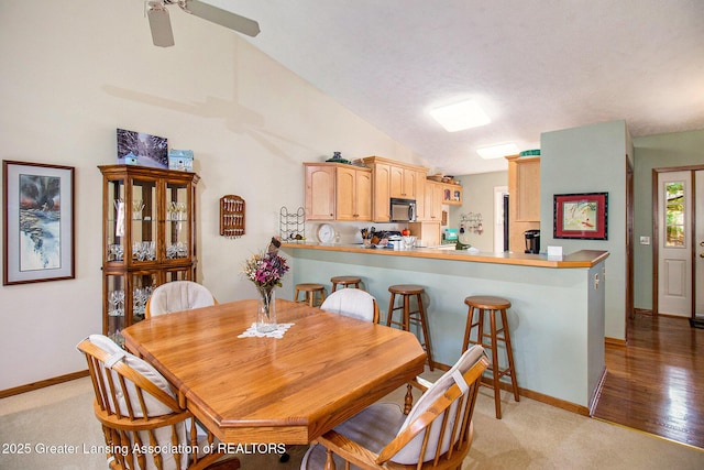 dining area featuring vaulted ceiling, baseboards, ceiling fan, and light colored carpet