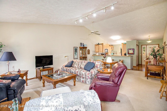 living room with a textured ceiling, light colored carpet, lofted ceiling, a ceiling fan, and track lighting