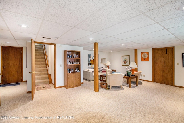carpeted living area featuring baseboards, a paneled ceiling, stairs, and recessed lighting