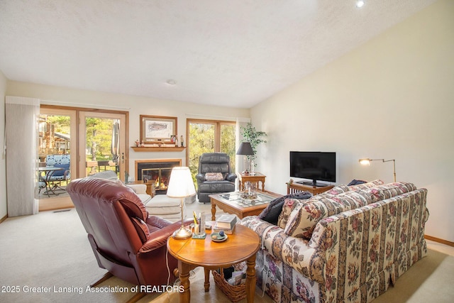 living room featuring light carpet, visible vents, baseboards, a glass covered fireplace, and lofted ceiling