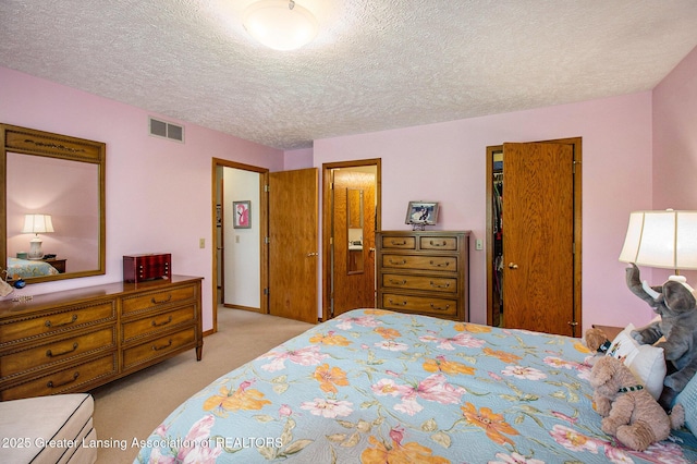 carpeted bedroom with a textured ceiling, visible vents, and a closet