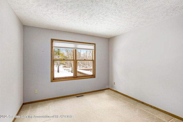 empty room featuring light carpet, baseboards, visible vents, and a textured ceiling