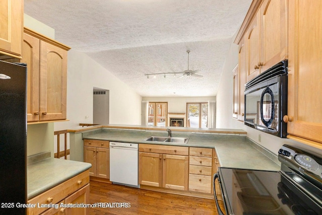 kitchen with a textured ceiling, a sink, black appliances, light brown cabinetry, and rail lighting