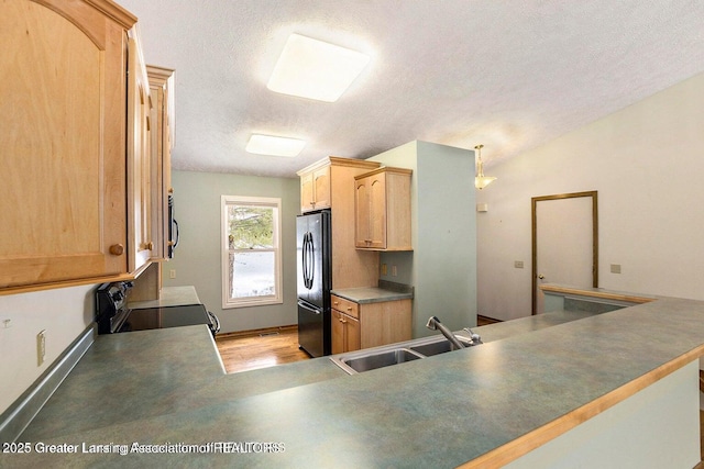 kitchen featuring a sink, a textured ceiling, light wood-style floors, light brown cabinets, and black appliances