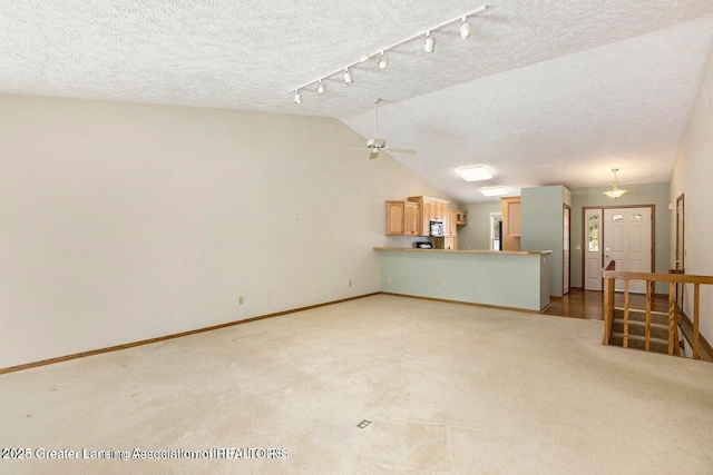 unfurnished living room featuring track lighting, ceiling fan, baseboards, and light carpet