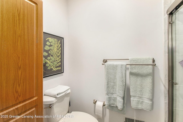 bathroom with toilet, an enclosed shower, and visible vents