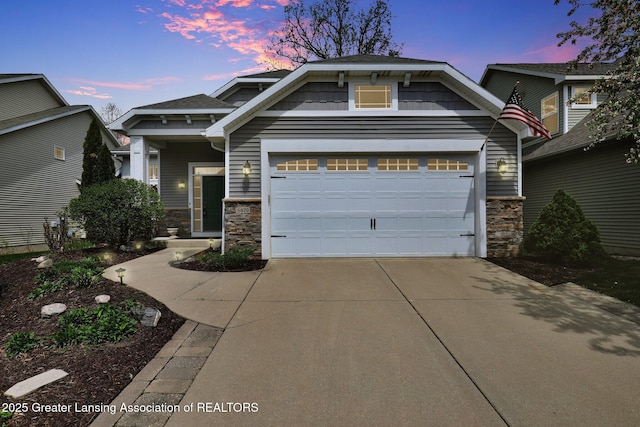 craftsman-style home featuring an attached garage, stone siding, and concrete driveway