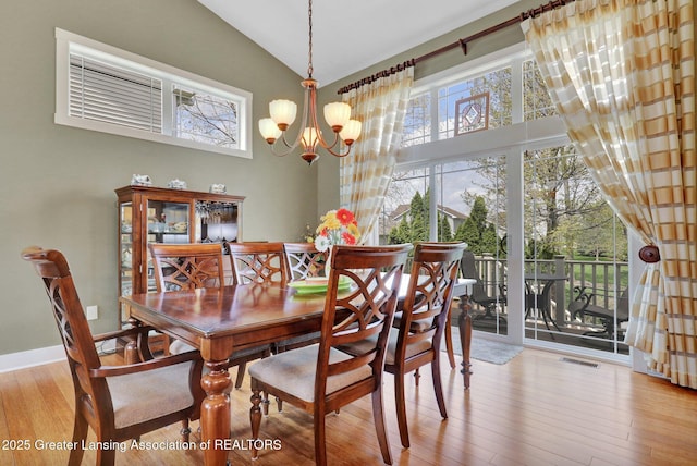 dining area featuring visible vents, a healthy amount of sunlight, an inviting chandelier, and wood finished floors