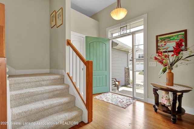 foyer entrance with baseboards, wood-type flooring, and stairs