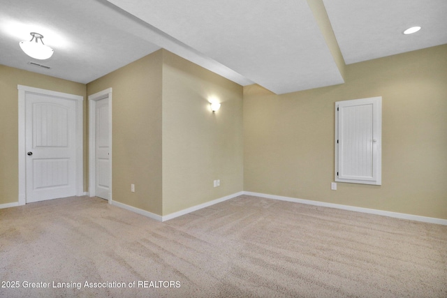 spare room featuring baseboards, light colored carpet, and visible vents