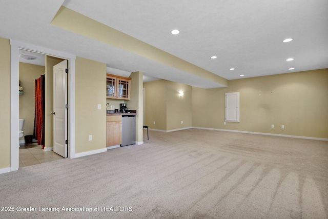unfurnished living room with indoor wet bar, recessed lighting, baseboards, and light colored carpet