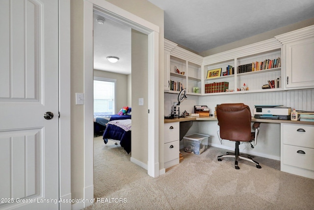 carpeted home office featuring built in study area and baseboards