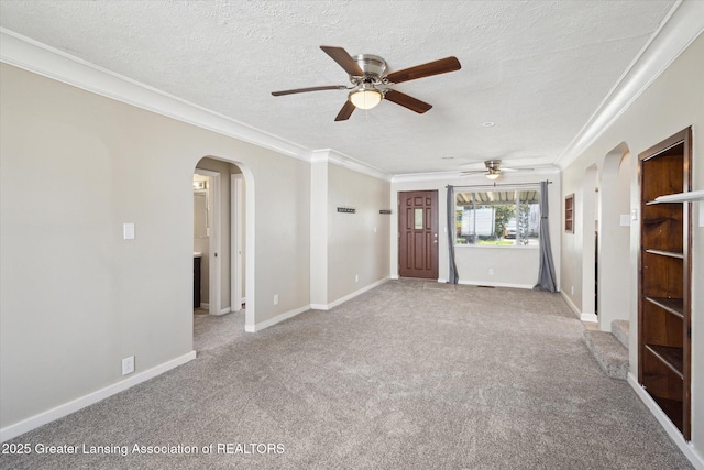 unfurnished living room with carpet floors, arched walkways, a ceiling fan, and ornamental molding