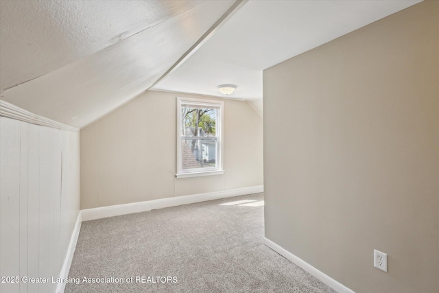 additional living space with baseboards, carpet flooring, and vaulted ceiling