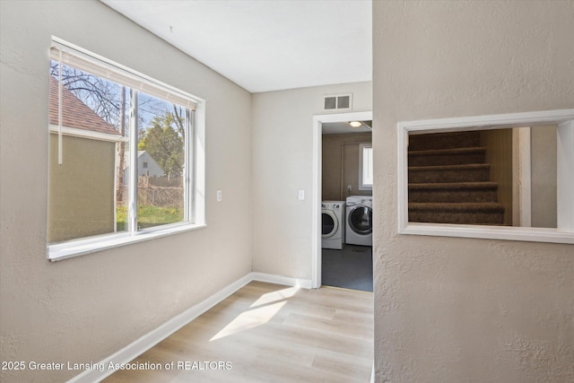laundry room with laundry area, a healthy amount of sunlight, wood finished floors, visible vents, and washer and clothes dryer