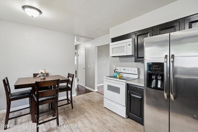 3427 W Jolly Rd, Lansing, MI 48911 - kitchen featuring white appliances, light wood finished floors, dark cabinets, and light countertops