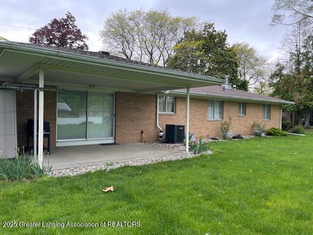 505 S Baker St, Saint Johns, MI 48879 - rear view of house with central AC unit, a lawn, a patio, and brick siding