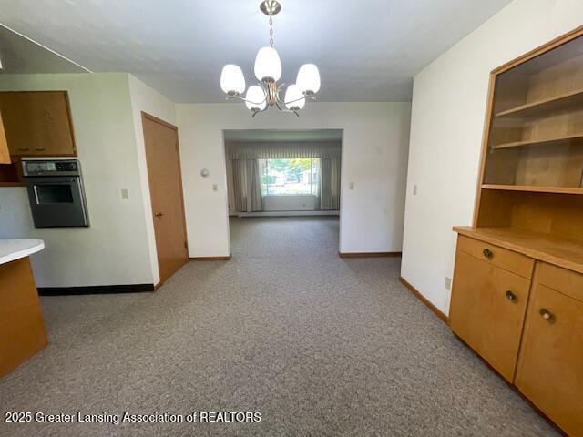505 S Baker St, Saint Johns, MI 48879 - unfurnished dining area with a chandelier, baseboards, and light colored carpet