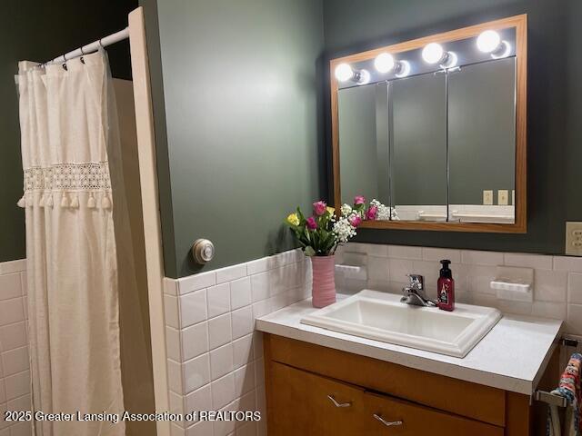 505 S Baker St, Saint Johns, MI 48879 - bathroom featuring vanity, tile walls, a wainscoted wall, and a shower with curtain