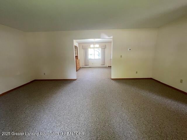 505 S Baker St, Saint Johns, MI 48879 - empty room with baseboards, a chandelier, a baseboard radiator, and carpet