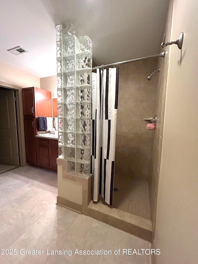 full bathroom featuring visible vents, vanity, and tiled shower