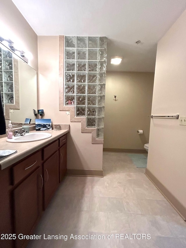 bathroom with toilet, vanity, and baseboards