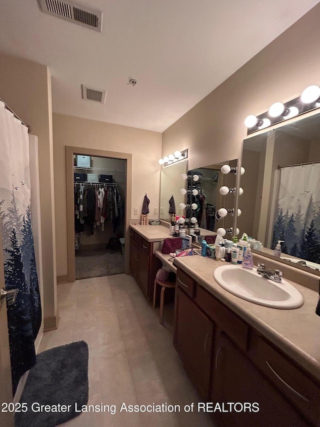 bathroom with a walk in closet, visible vents, and vanity