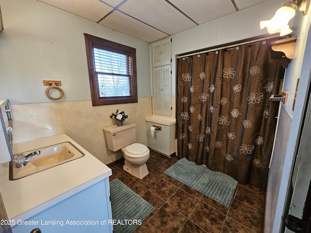 bathroom featuring tile patterned floors, toilet, vanity, curtained shower, and a paneled ceiling