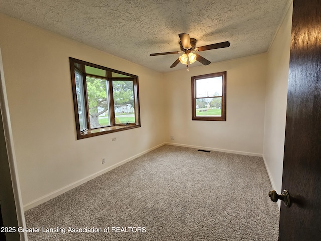 carpeted empty room with a textured ceiling, ceiling fan, baseboards, and visible vents