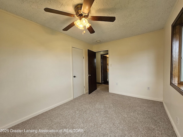 carpeted spare room with a textured ceiling, a ceiling fan, and baseboards