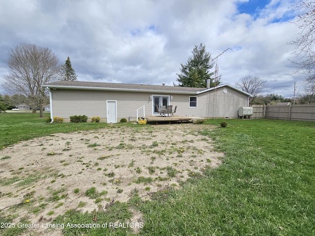 back of property with a lawn, a deck, and fence