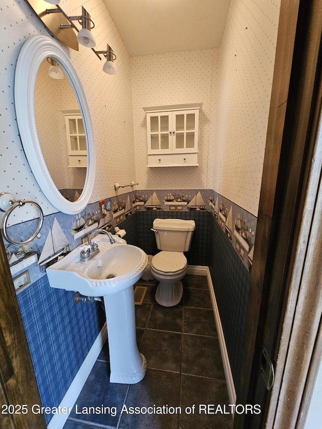 bathroom with toilet, wallpapered walls, and tile patterned floors