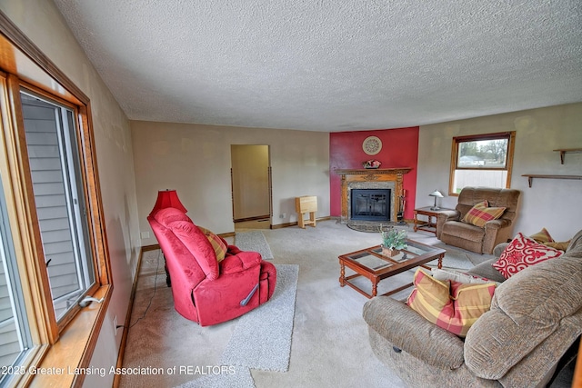 carpeted living area with baseboards, a textured ceiling, and a glass covered fireplace