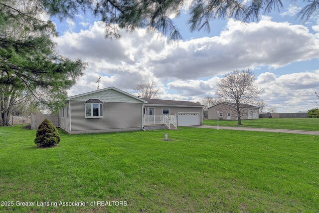 exterior space featuring driveway, fence, a front lawn, and an attached garage