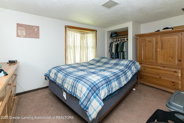 bedroom featuring light colored carpet, a closet, baseboards, and a textured ceiling