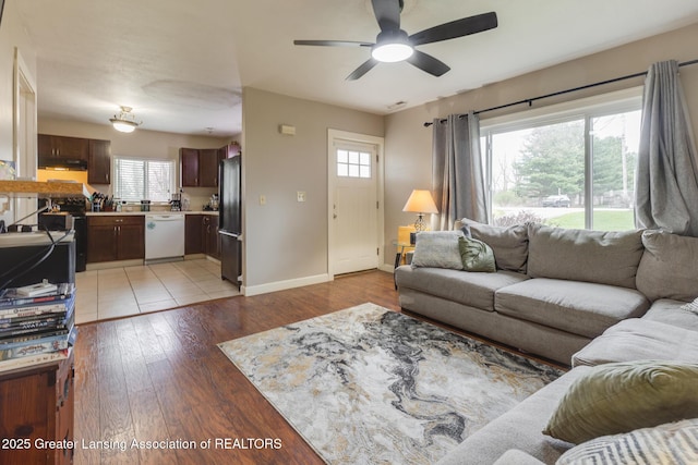 living area with ceiling fan, baseboards, visible vents, and light wood-style flooring